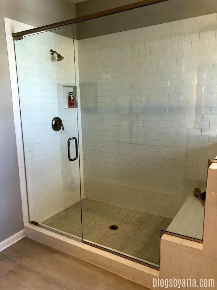 large walk-in shower with subway tile and bench